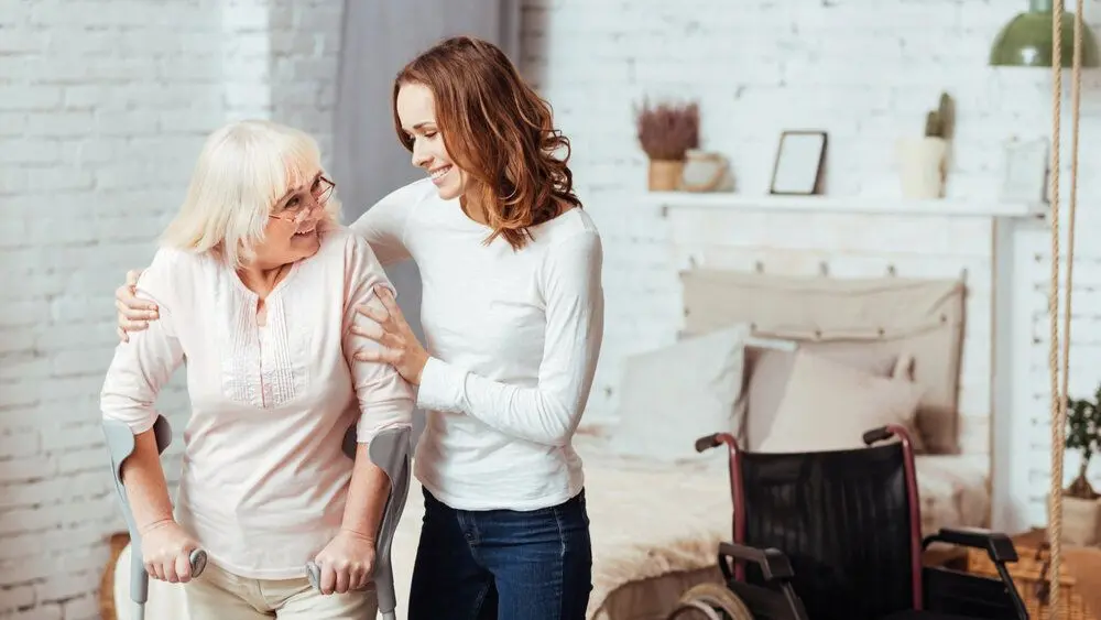 A volunteer helping an elderly lady walk