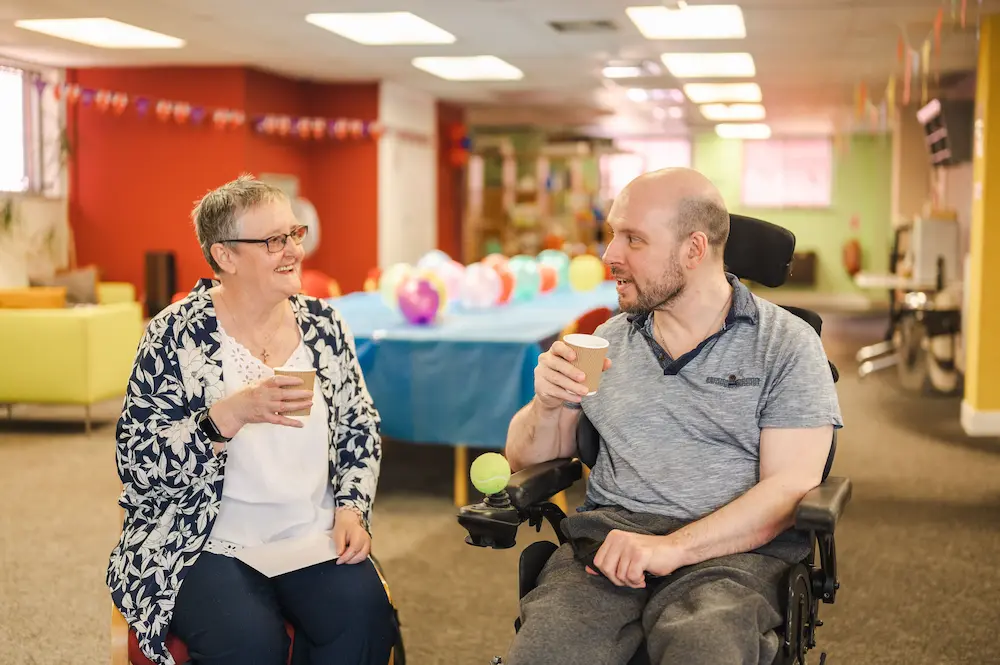 Female carer and man drinking tea together