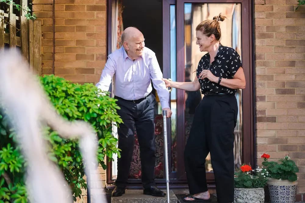Female carer and older man at front door