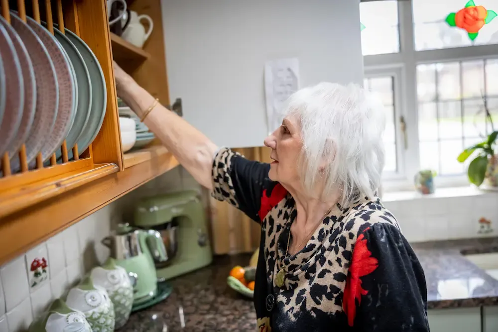 Older woman reaching for plates in kitchen