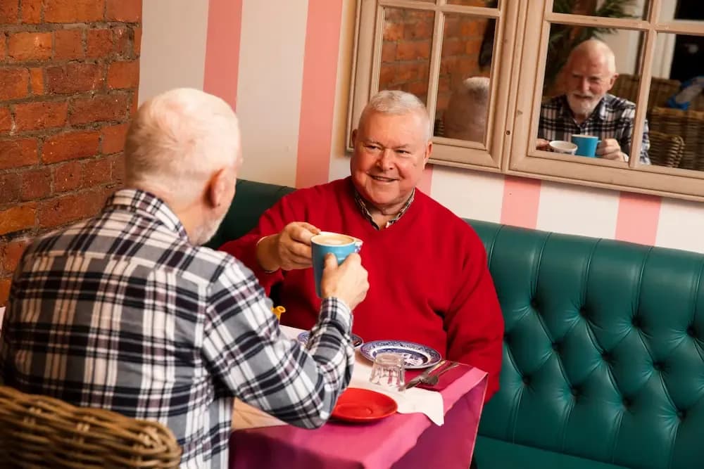 Two older men drinking hot drinks