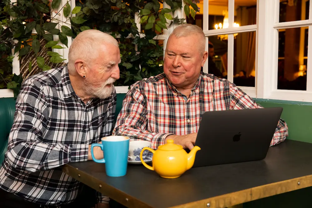 Two older men using a laptop together