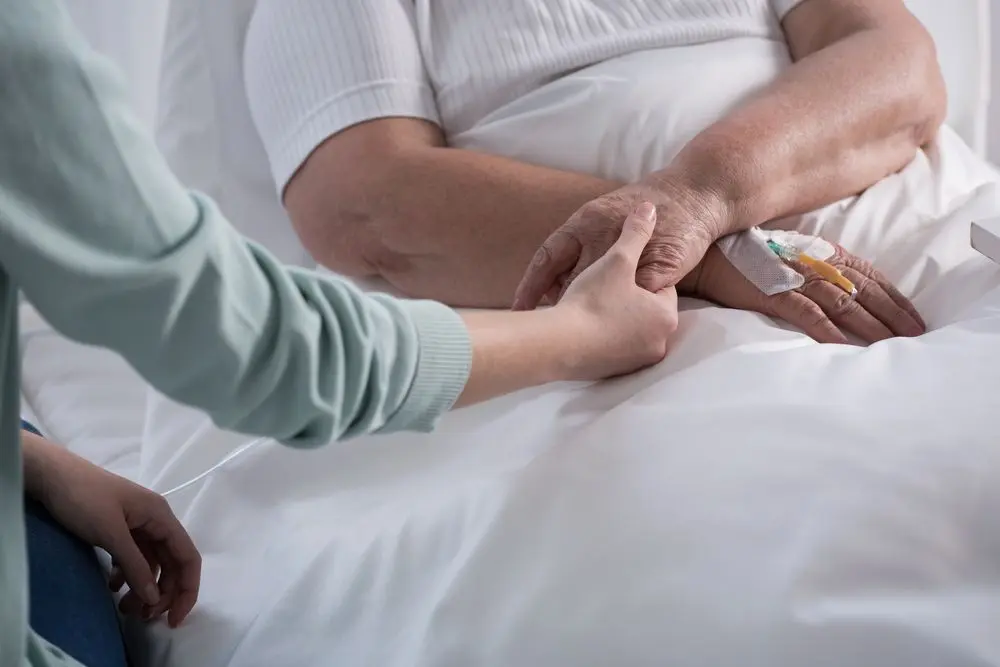 Two people holding hands while one receives care