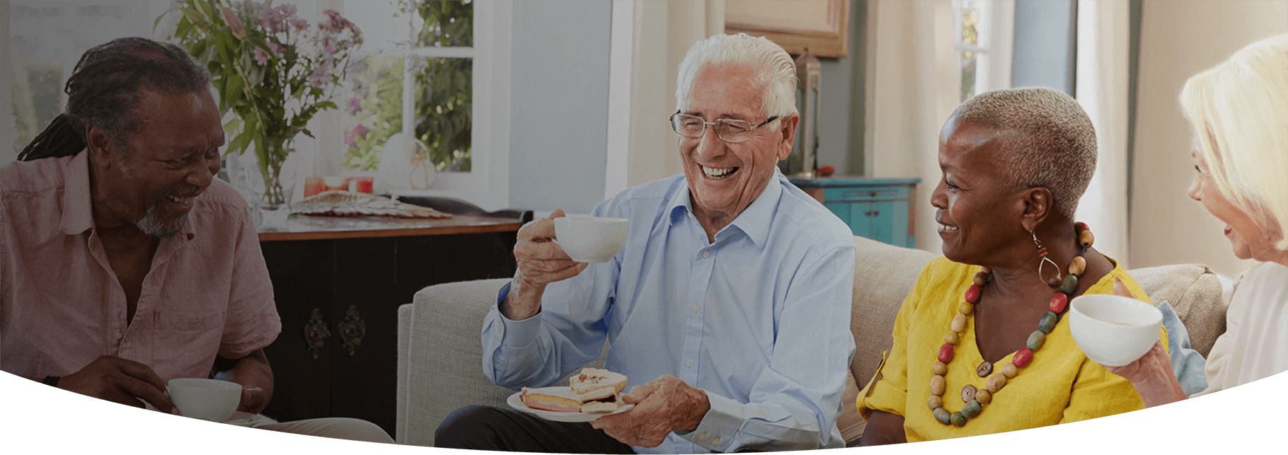 A group of elderly people chatting and laughing over a cup of tea