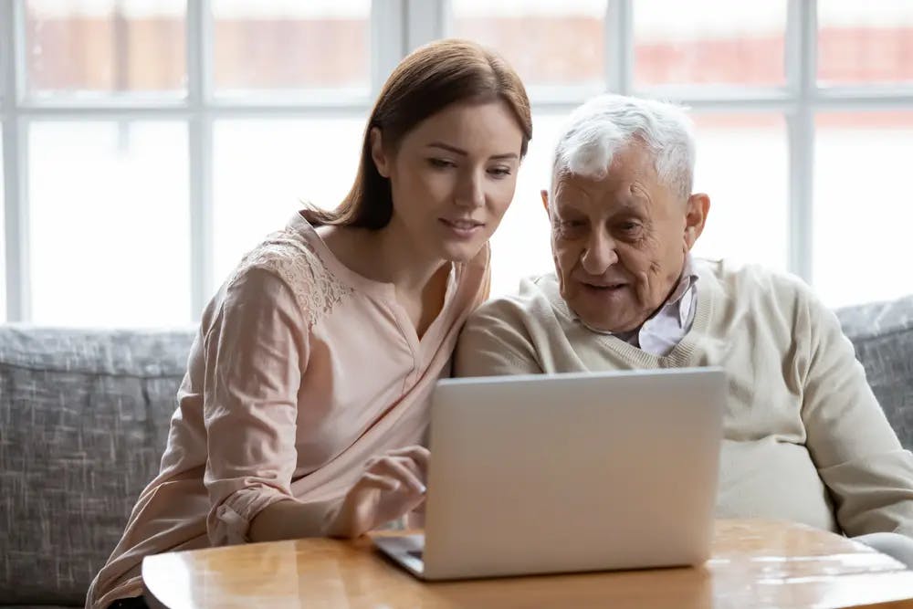 Daughter and elderly father using a laptop together