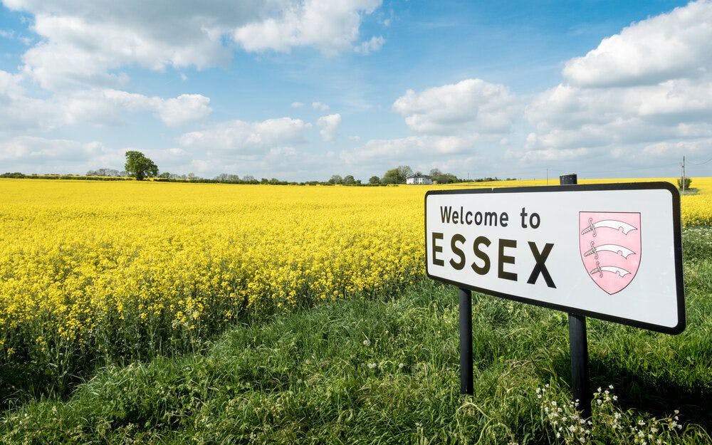A welcome to Essex sign in front of a field of yellow flowers