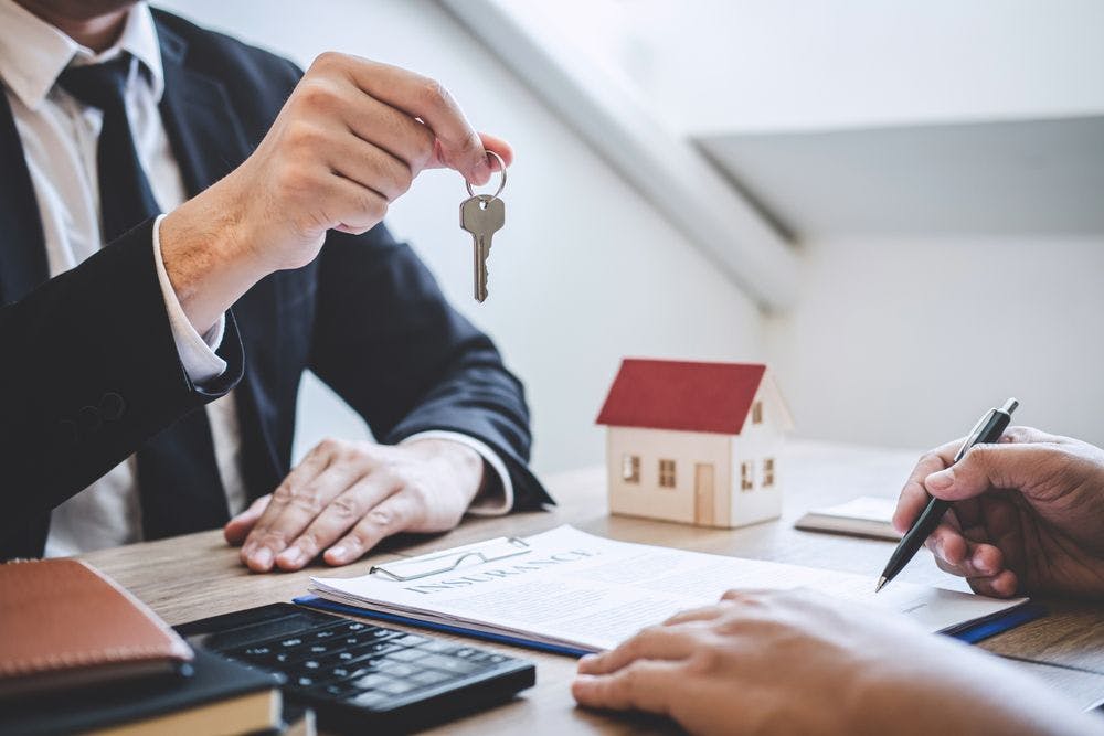 Estate agent giving house keys to an older adult