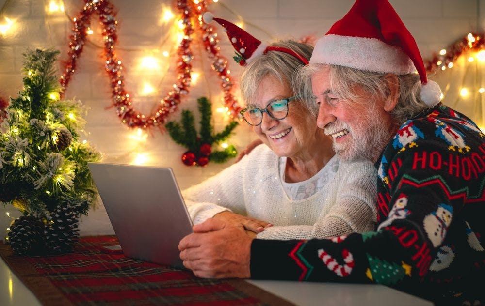Older couple wearing santa hats and looking at a laptop