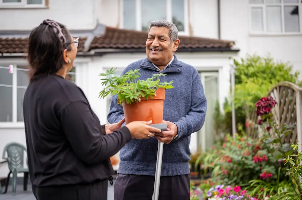 Older man and female carer gardening together