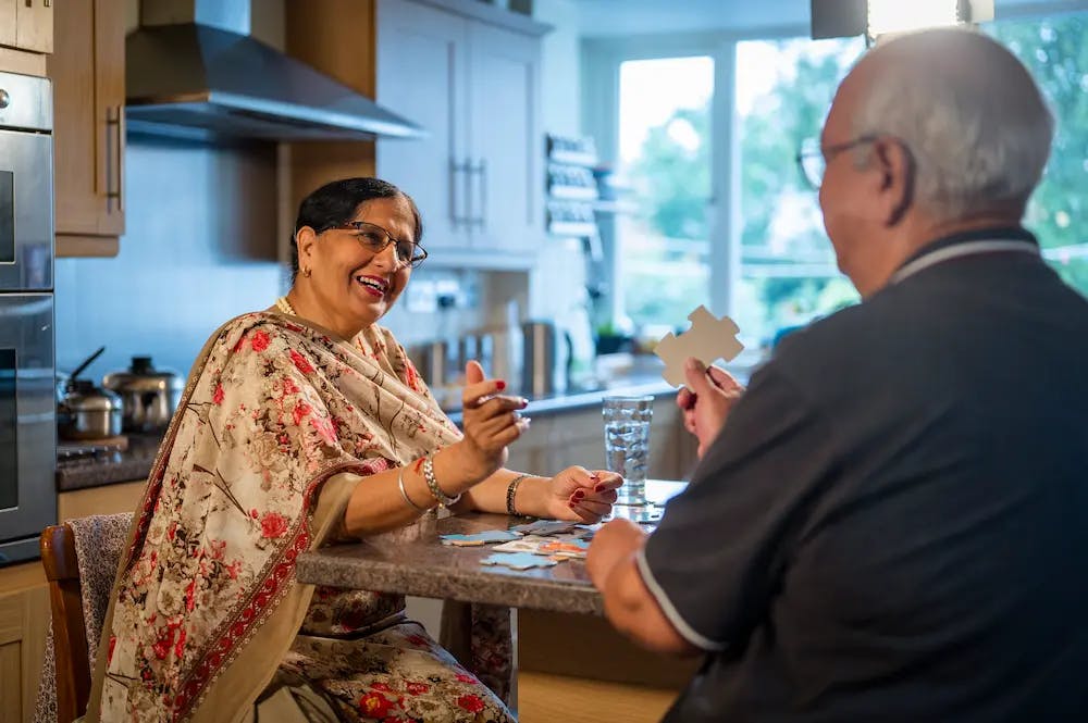 Older man and woman doing a jigsaw at a kitchen table