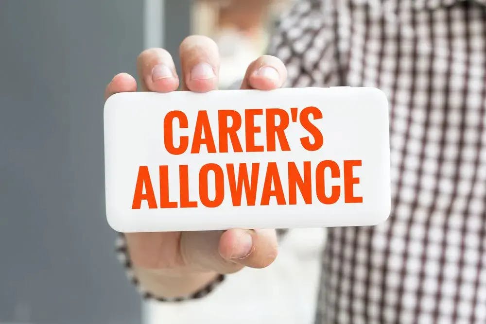 Person holding a Carer's Allowance sign