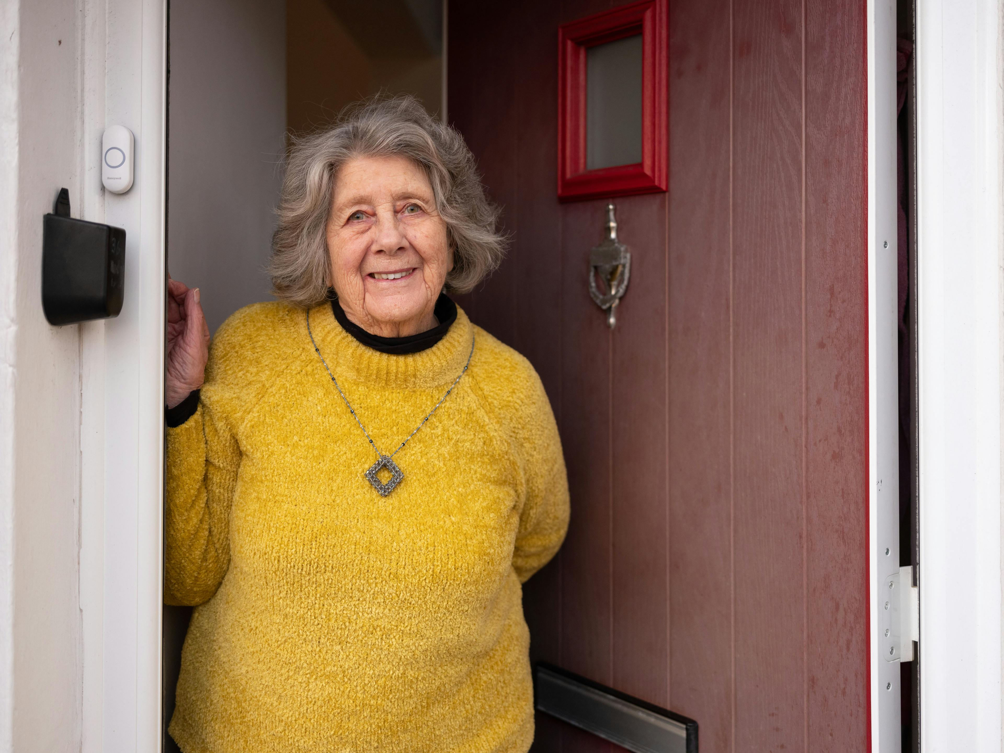 Older woman standing in her doorway