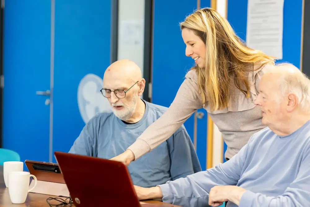 Two old men and a younger woman using a laptop together