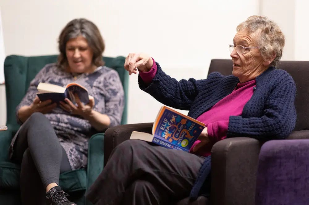 Two older women reading together