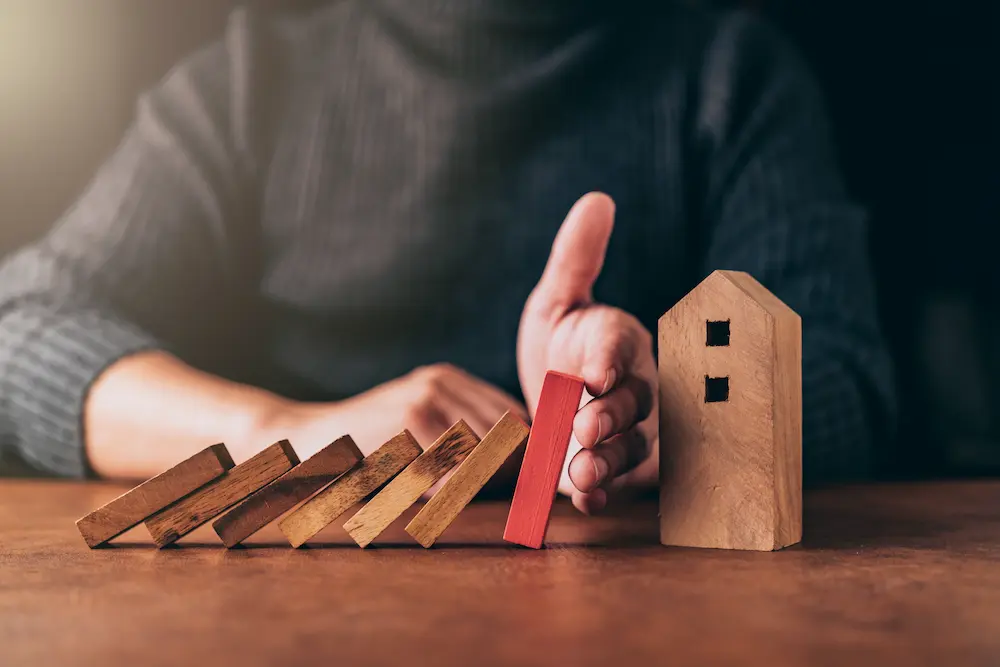 Wooden domino chain going towards a small wooden house