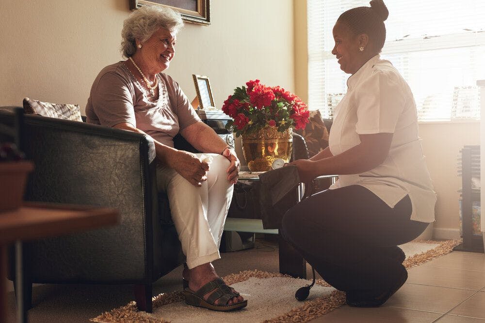 A nurse speaking to a care home resident in her room