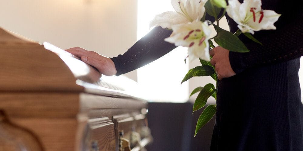 A woman touching a coffin at a funeral