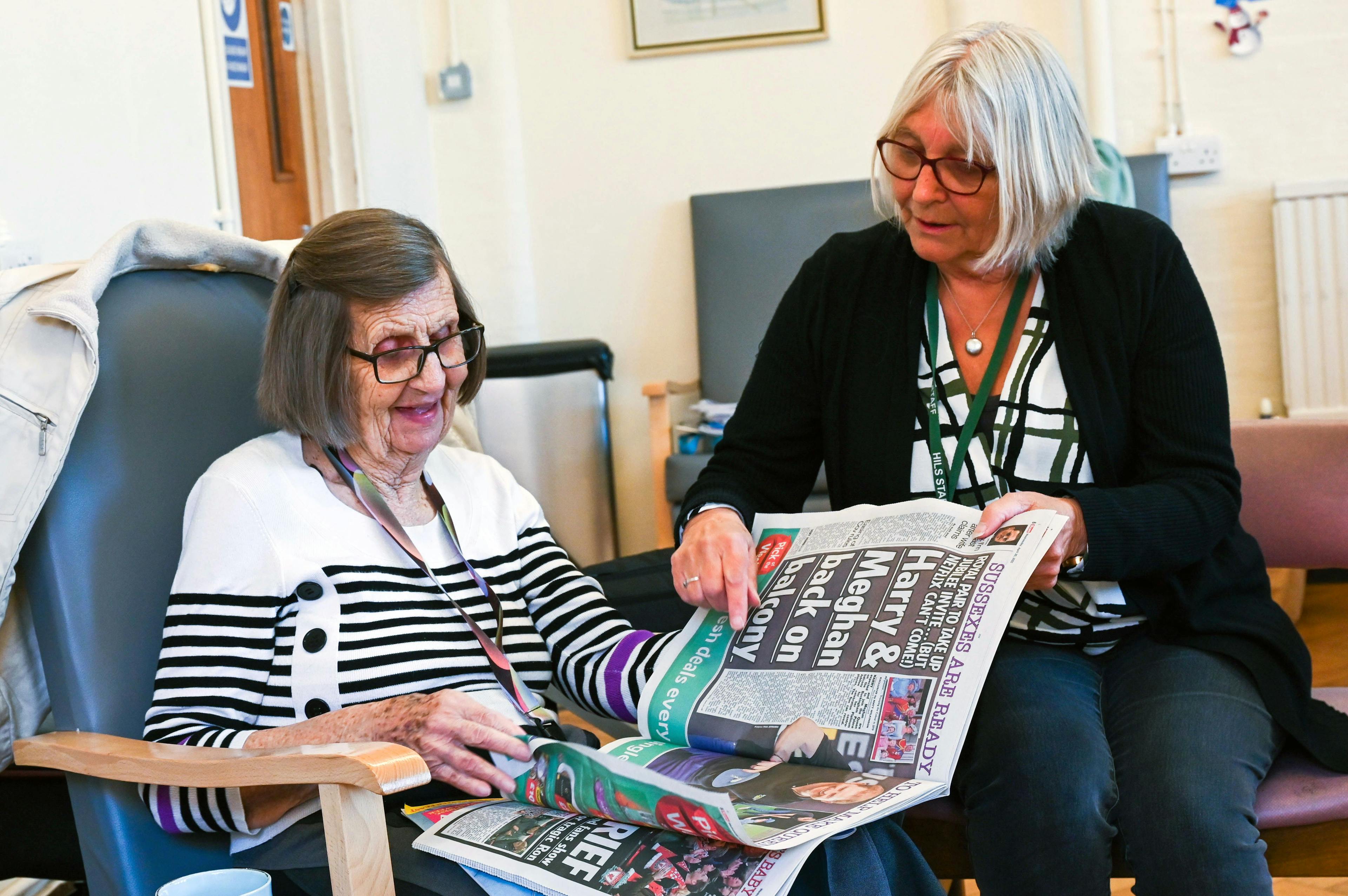 Volunteer helping a resident read the newspaper