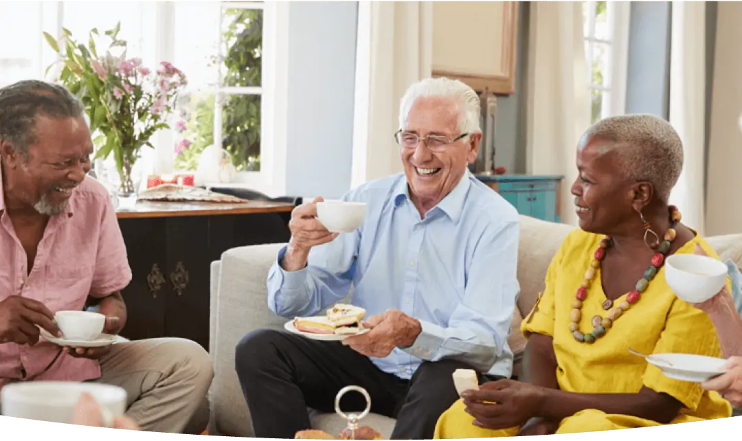 Some older people laughing while drinking tea